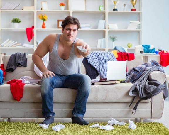 young man squatting in a messy room